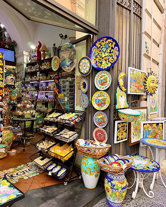 Un negozio di ceramiche colorate con piatti, vasi e piastrelle dipinte a mano
