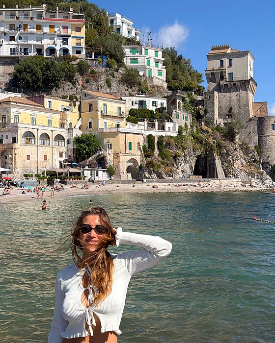 Una ragazza in acqua con il borgo di Cetara e la spiaggia dietro