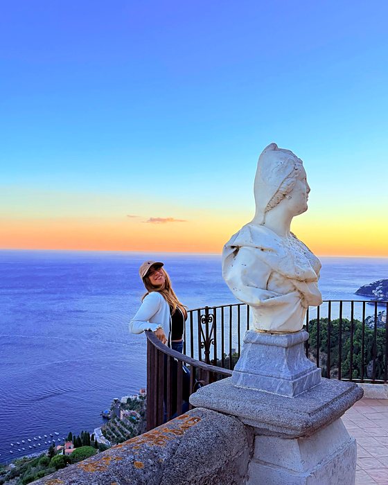 Una ragazza al tramonto sulla Terrazza dell'Infinito, con il busto di marmo e il mare