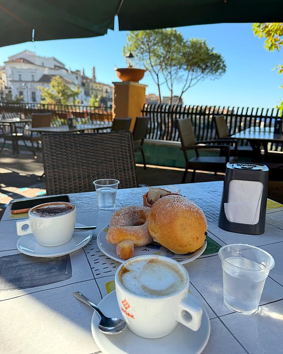 Una colazione con cappuccino e cornetti su un tavolino con vista