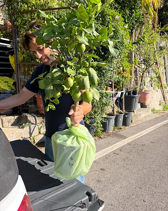 Riccardo con in mano una piantina di limone, davanti a un'auto