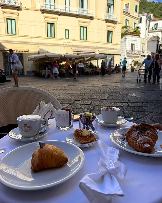 Un tavolino all'aperto con cappuccini e cornetti nella piazza