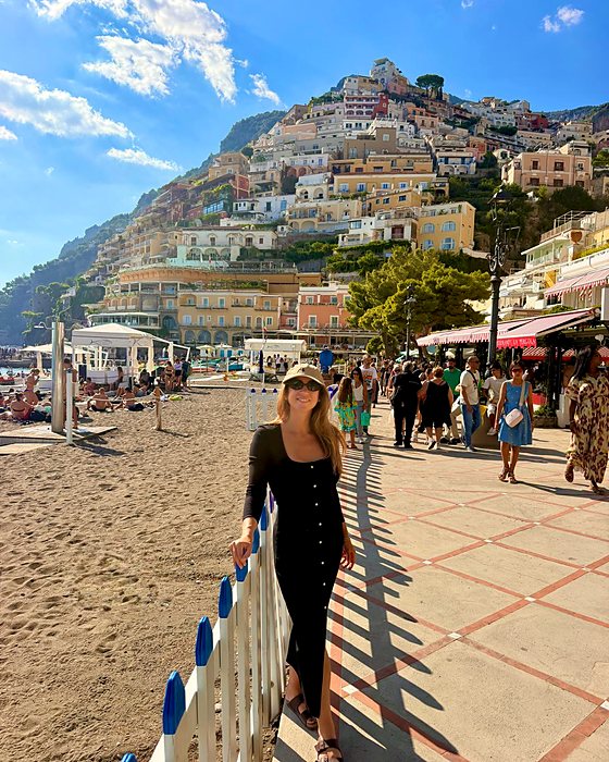 Una ragazza sulla spiaggia di Positano con il paese sulla collina