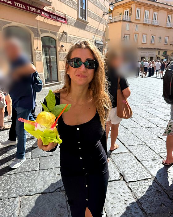 Una ragazza con un sorbetto servito in un limone, in una via di Amalfi