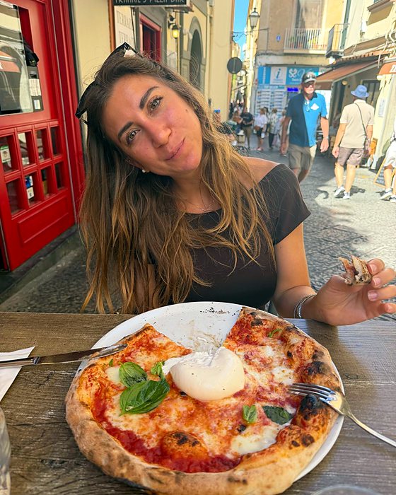 Una ragazza con una pizza con bufala in una via di Sorrento