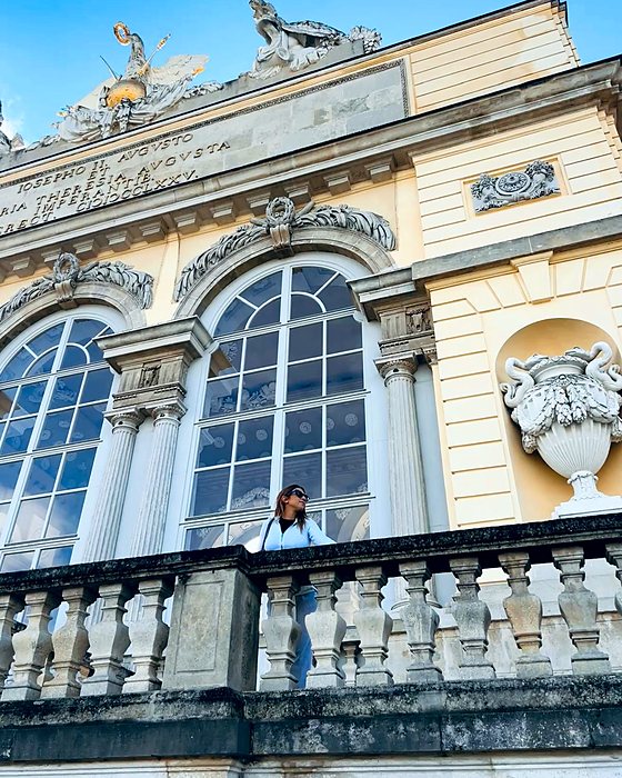 A historic building with statues and a balustrade, with a person leaning out
