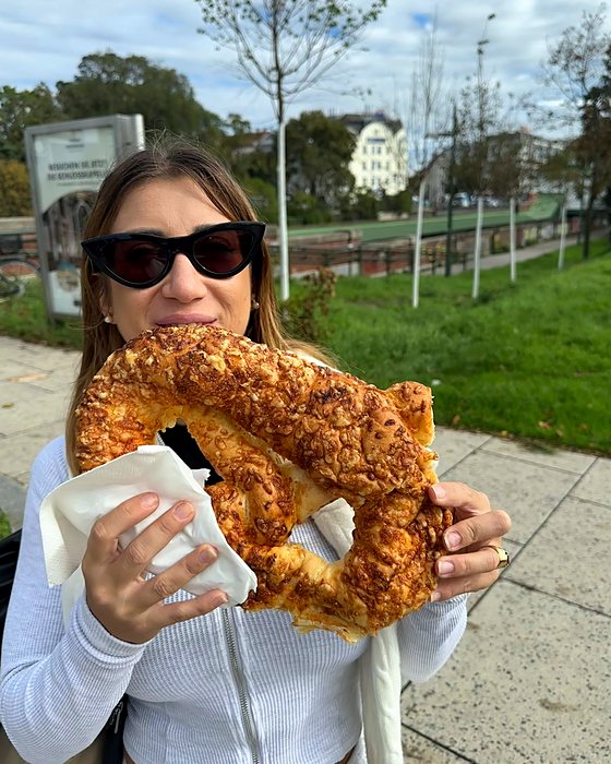 A giant cheese pretzel eaten in a park