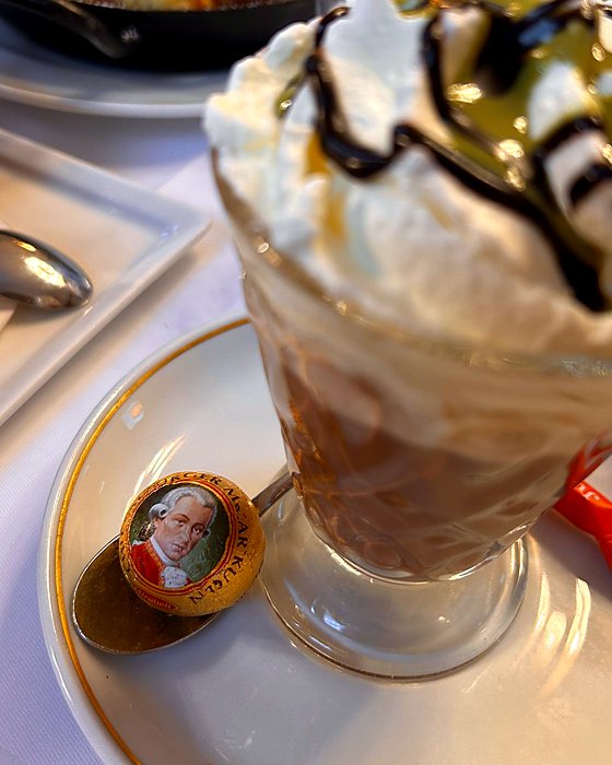 A glass with cream and chocolate and a Mozart ball on the spoon