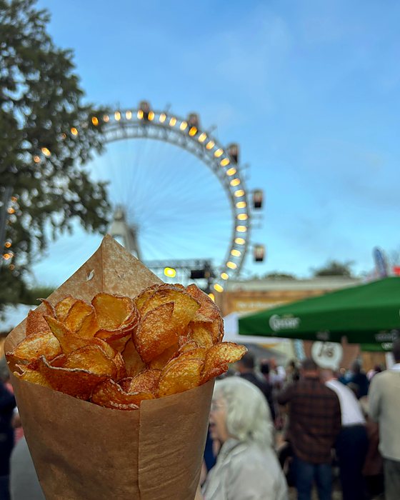 A paper cone of chips with the Prater Ferris wheel behind it
