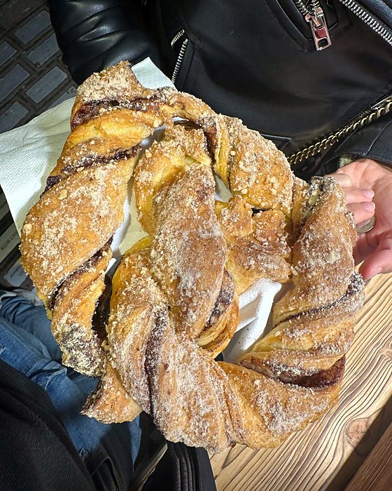 A sweet braided pastry covered in sugar, held in the hand