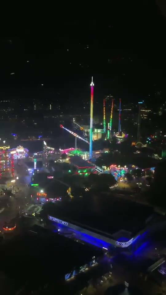 The Prater at night seen from above, with coloured lights and the Ferris wheel in the distance